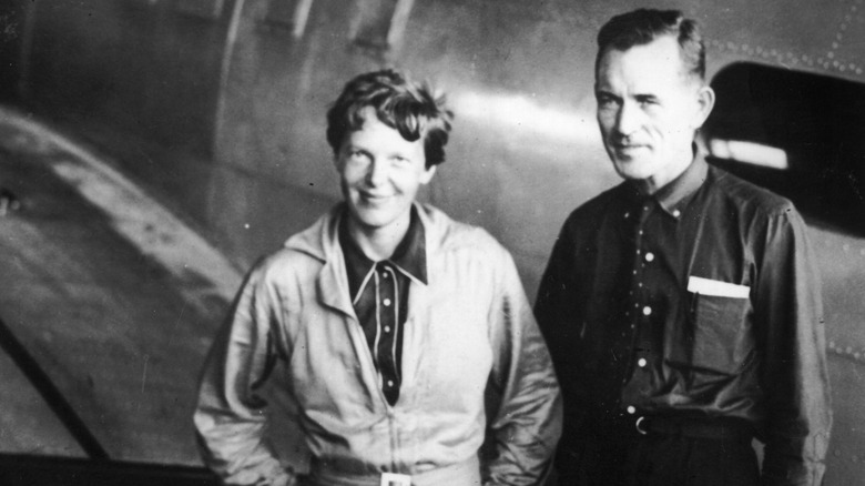 Amelia Earhart and Fred Noonan smiling by plane