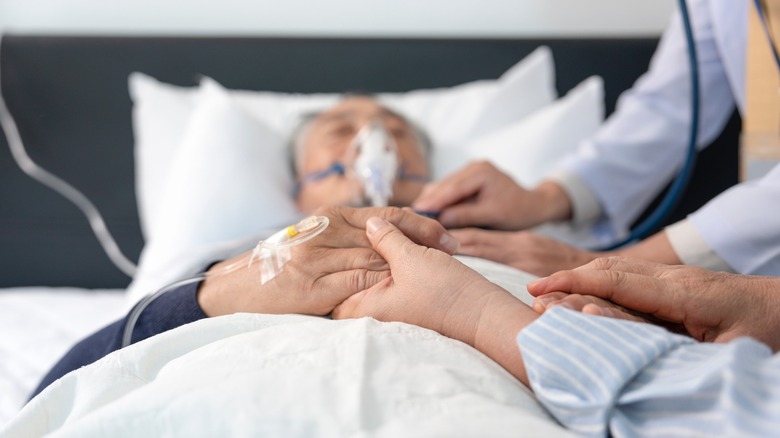 People holding hands of a patient dying in hospital