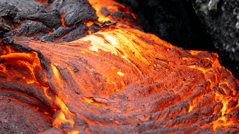 A close-up photo of white-hot lava flowing out of black rock