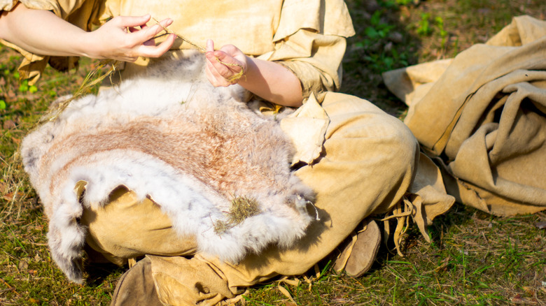 Person making clothing from animal fur