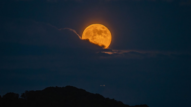 Full moon rising behind clouds