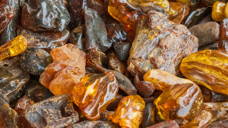 Polished and unpolished amber stones are seen together in a pile