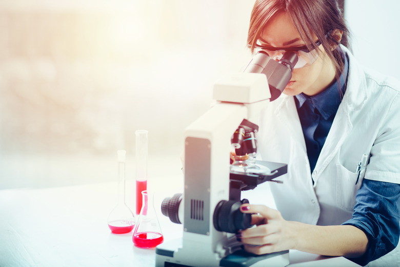 Female researcher looking through a microscope in a laboratory