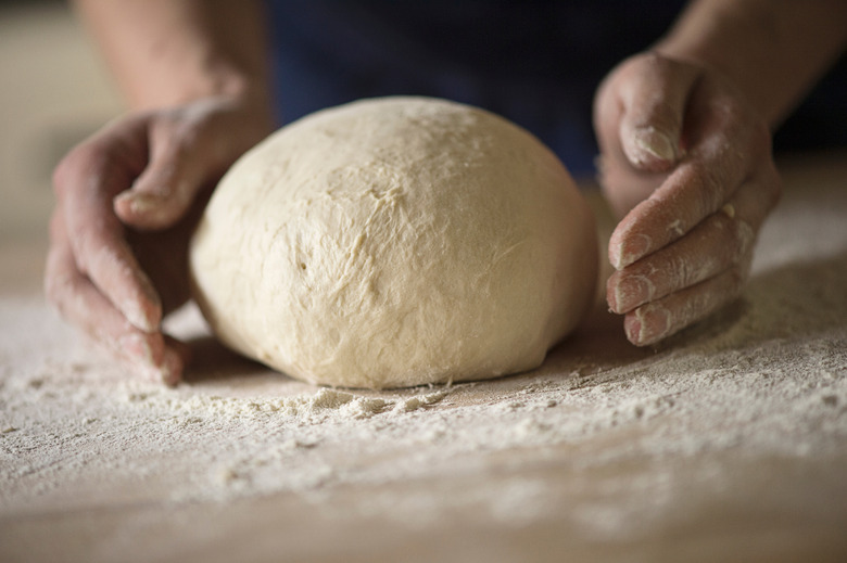 Close up of hands shaping bread dough