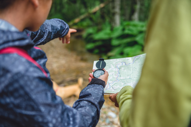 Daughter and mother hiking in forest and using compass