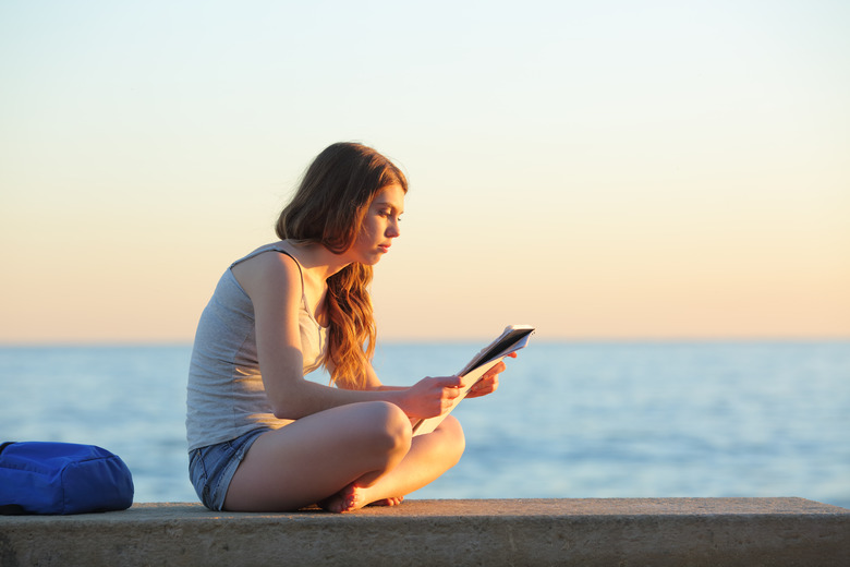 Profile of a student studying reading notes on the beach