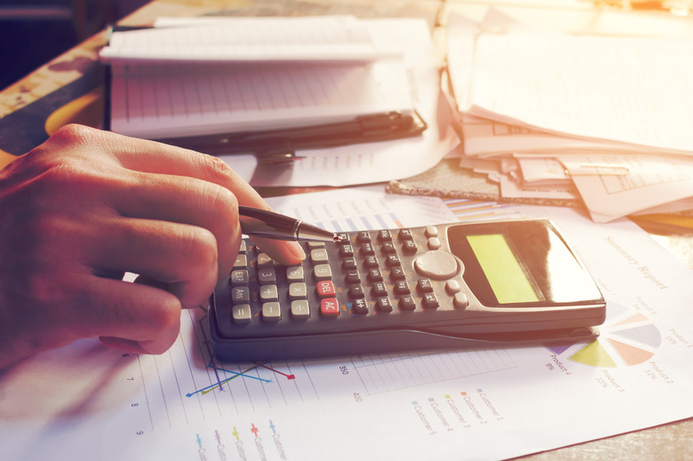 Close up man using calculator and doing finance in home