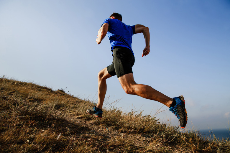 dynamic running uphill on trail male athlete runner side view