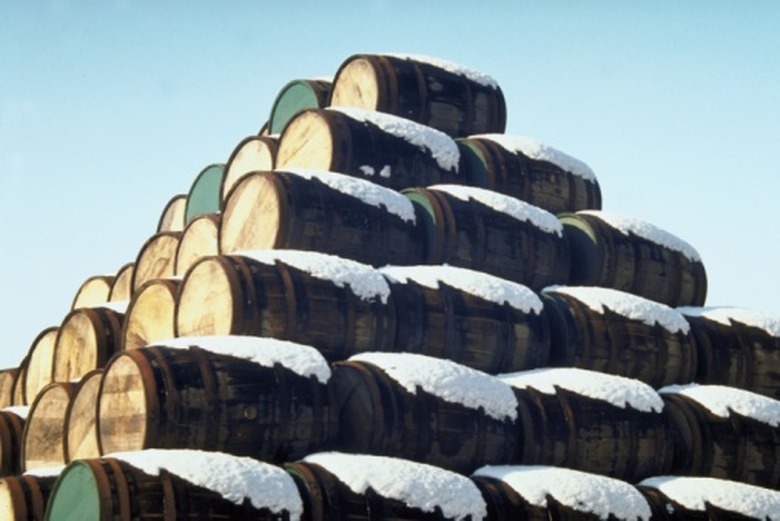 A pyramid of barrels with snow on them.