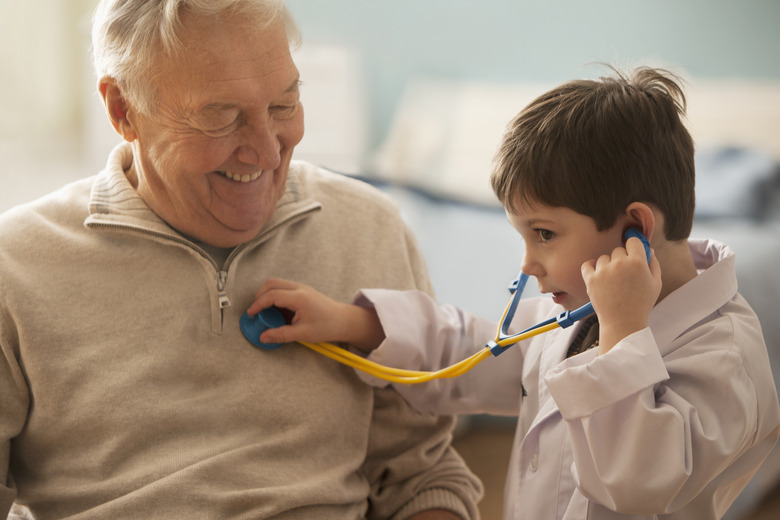 Caucasian boy listening to grandfather's heartbeat with stethoscope