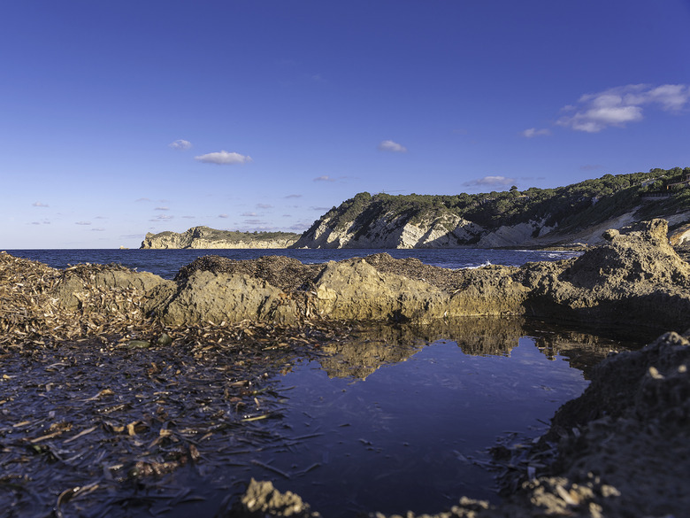 a tide pool of water with the cliffs in the background over the sea