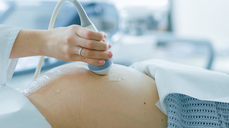 In the Hospital, Close-up Shot of the Doctor Doing Ultrasound / Sonogram Scan to a Pregnant Woman. Obstetrician Moving Transducer on the Belly of the Future Mother.