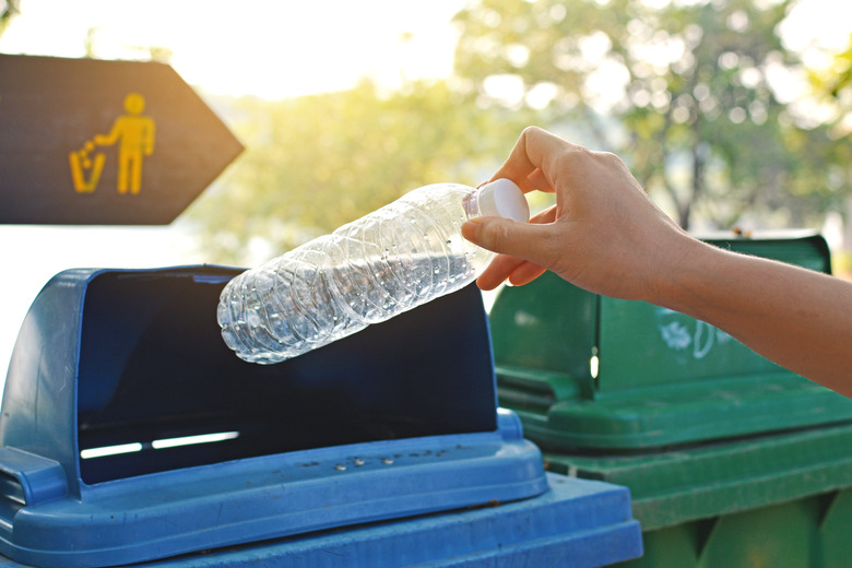 Close up hand holding empty bottle into the trash