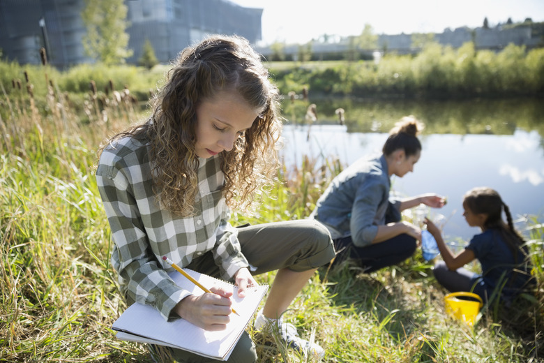 Schoolgirl taking notes on field trip at pond