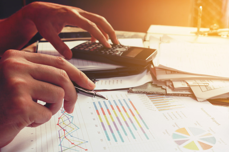 Businesswoman using calculator with holding pen and thinking abo