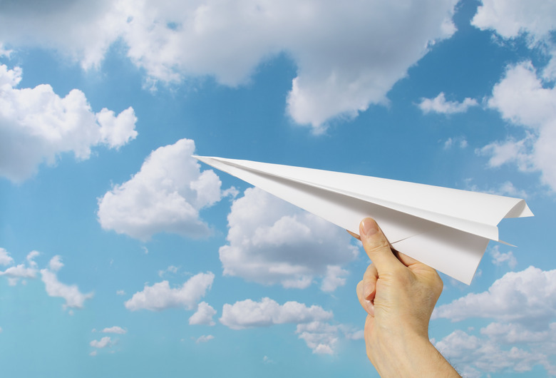 Holding a paper airplane against blue sky with copy space