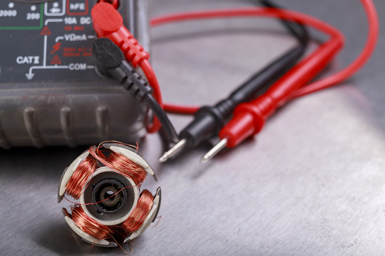 Damaged electric motor rotor and electric meter. Measurement work in an electrical workshop. Metallic background.