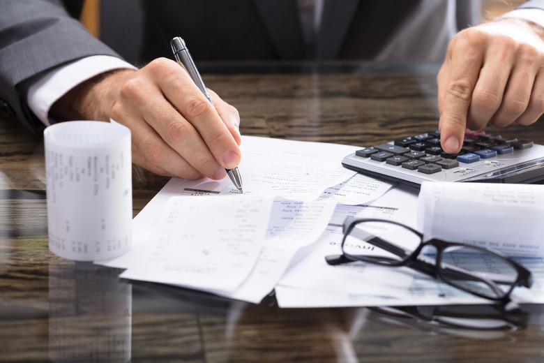 Close-up Of A Businessperson Calculating Receipt