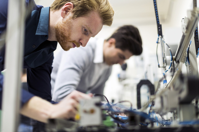 Two young handsome engineers working on electronics components