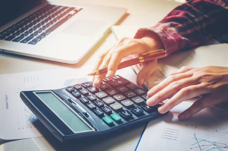 Businessman's hands with calculator at the office and Financial data analyzing  counting on wood desk