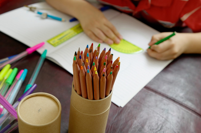 Boy (6-8) using protractor, focus on pot of pencils, close up