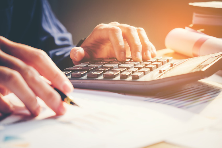 Businessman's hands with calculator at the office and Financial data analyzing  counting on wood desk