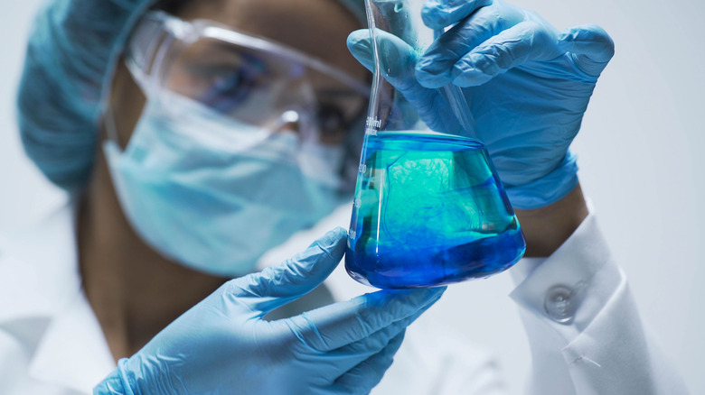 Researcher watching chemical reaction after adding test material into flask