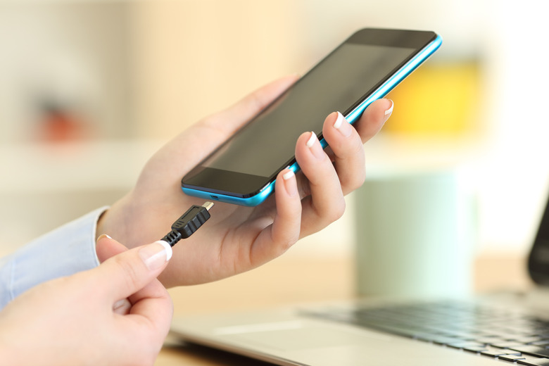 Woman's hands plugging a charger on a smart phone