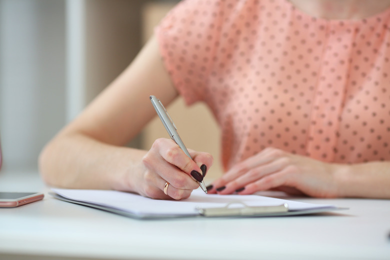 Woman performing calculations with paper, pen and calculator.