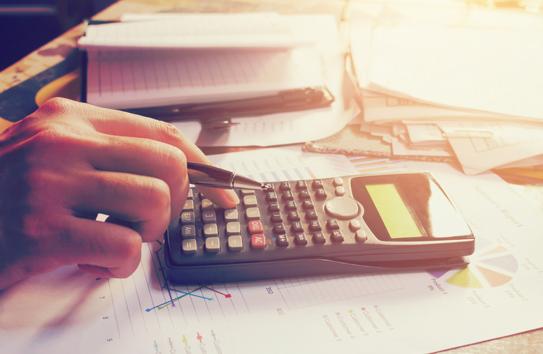 Hand man pressing on calculator with calculation about tax annual at home office.