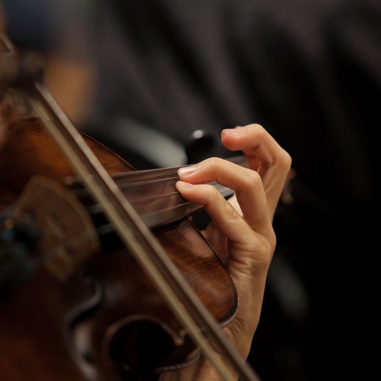 The girl's hand on the strings of a violin