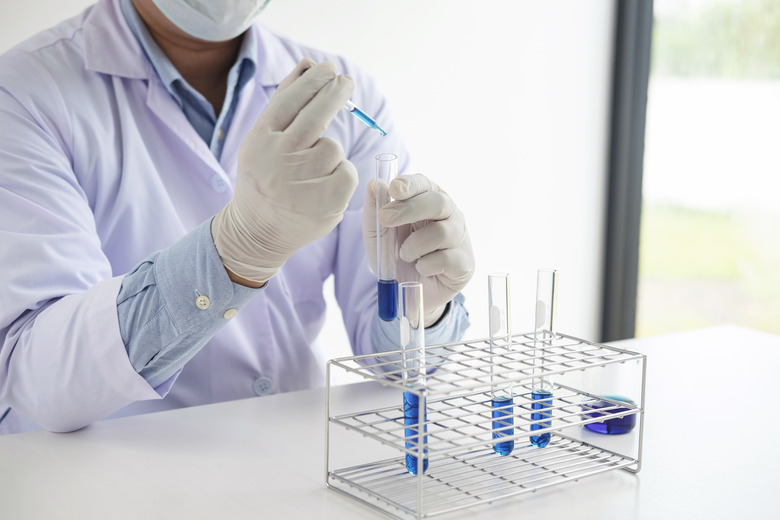 Scientist or medical in lab coat holding test tube with reagent with drop of color liquid over glass, Biochemistry laboratory research