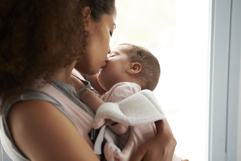 Close Up Of Mother Cuddling Baby Daughter At Home