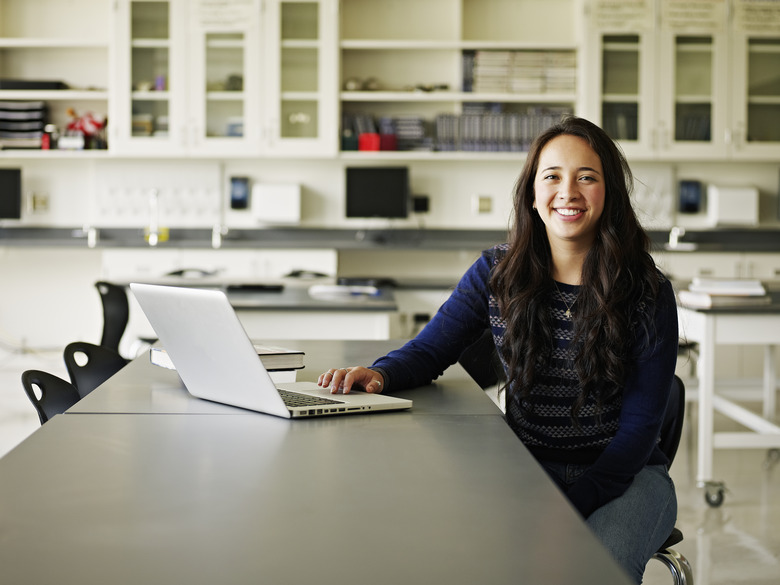 A smiling woman with a computer at a work desk