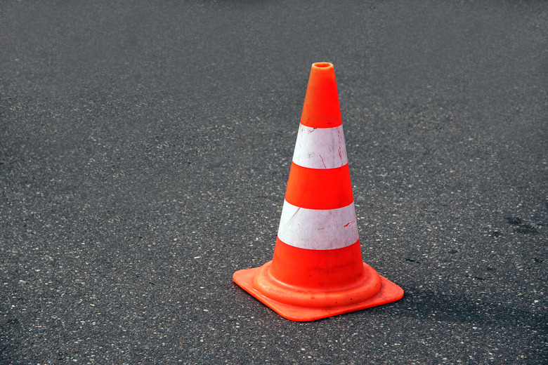 traffic cone, white and orange  on gray asphalt, copy space