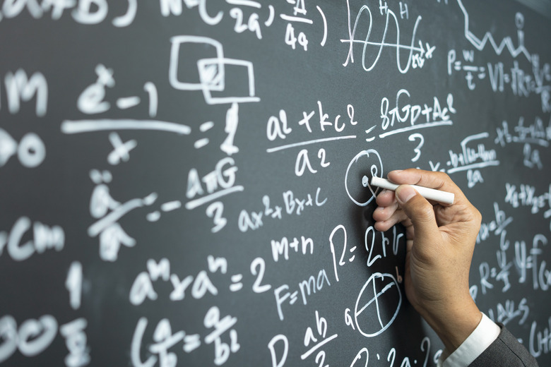 professor writing on the board while having a chalk and blackboard lecture (shallow DOF; color toned image)