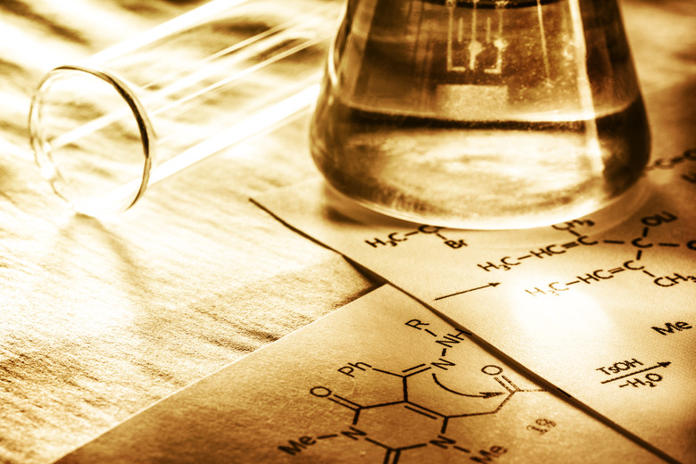 Beaker and test tube sitting on top of chemistry papers