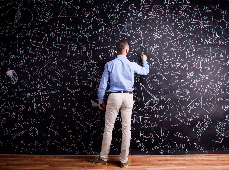 Man writing on big blackboard with mathematical symbols