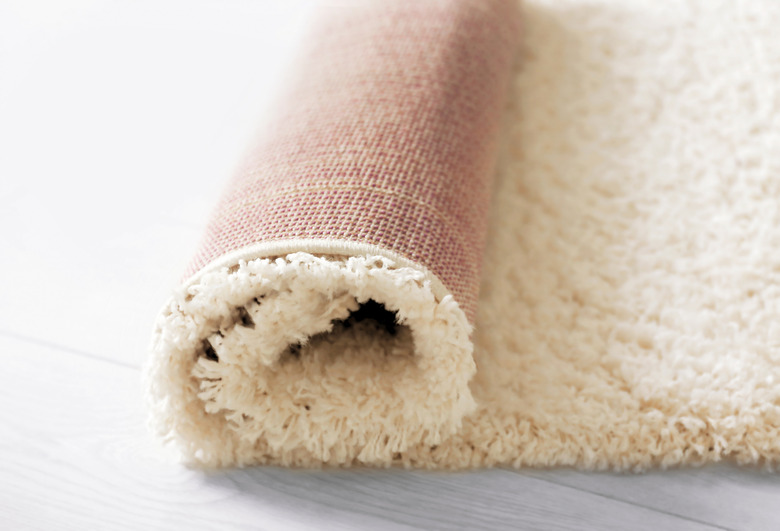 Rolled white carpet on wooden floor, closeup