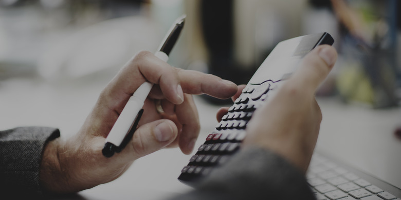 A hand holding a pen and a calculator