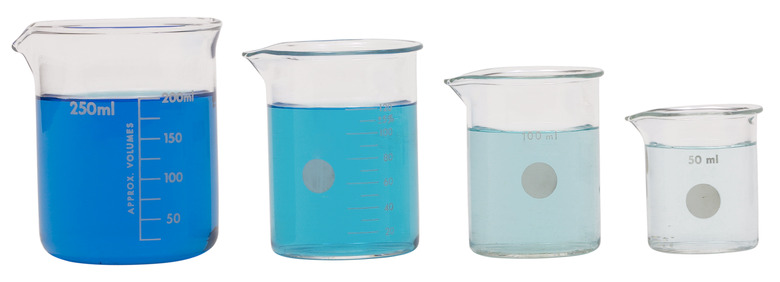 Four beakers from small to large containing different colored blue liquid