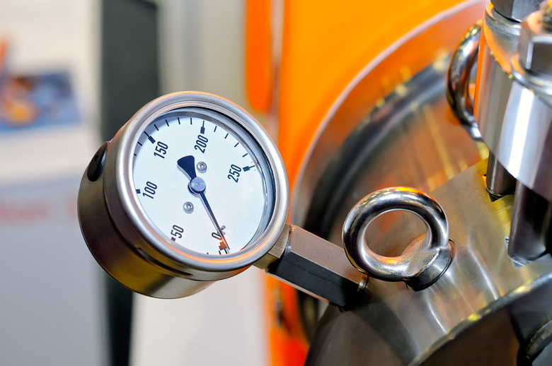 Pressure gauge on a blurry industrial background.