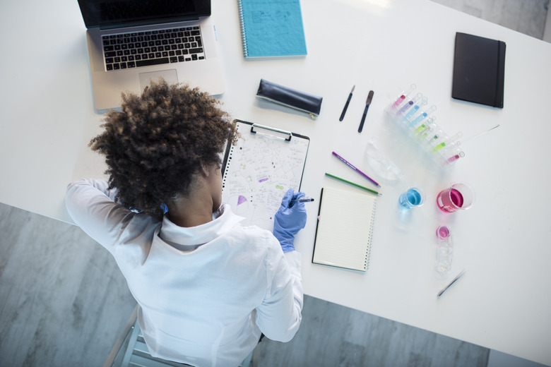 Female scientist writing on clipboard at desk