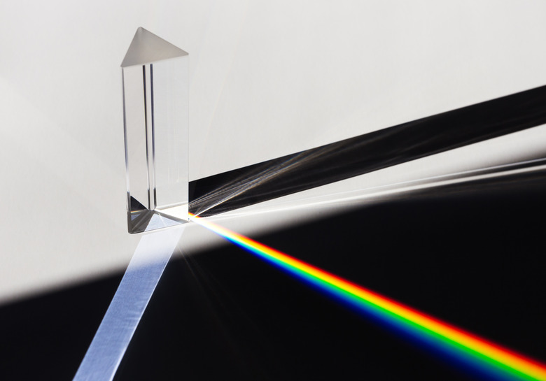 A prism dispersing sunlight splitting into a spectrum on a white background