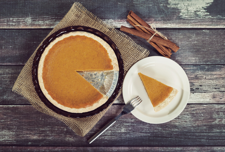 Pumpkin pie with cinnamon sticks against rustic wooden table