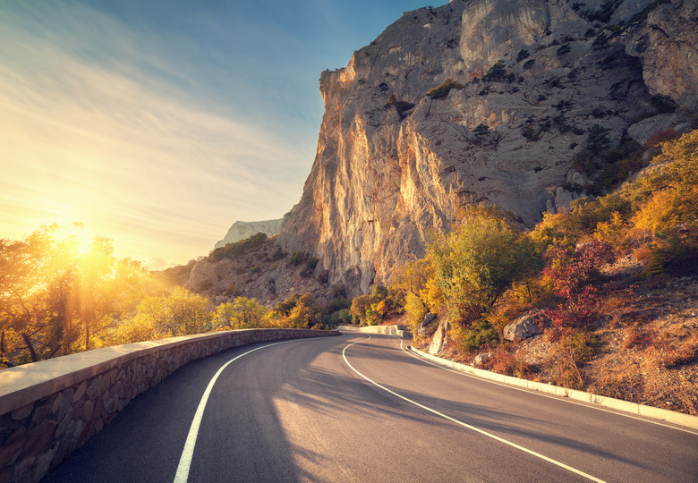 Asphalt road in autumn forest at sunrise. Crimean mountains