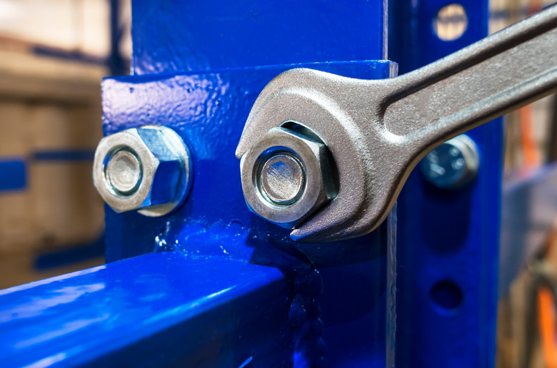 Wrench tightening the chrome nut on the blue metal structure (shell)