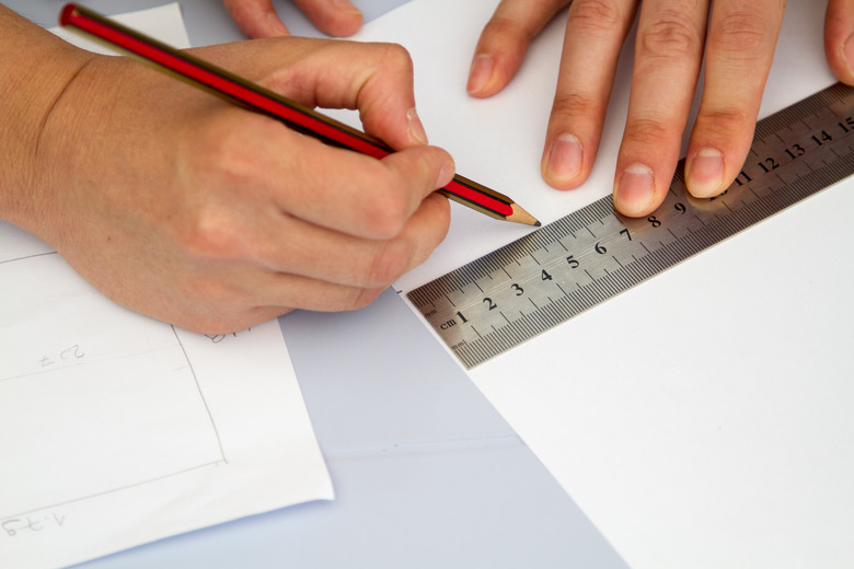 hands holding ruller and pencil over sheme on the table