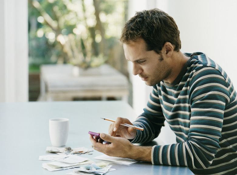 Man Sitting at a Table Using a Calculator