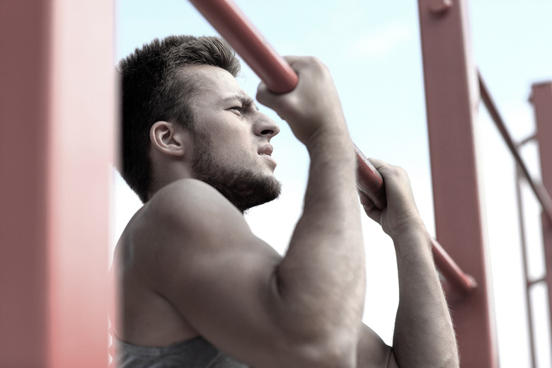 young man exercising on horizontal bar outdoors